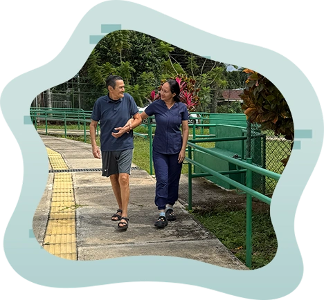 Persona Adulto Mayor acompa&ntilde;ado de una asistente y representando el bienestar recibido en el Hogar PAM de Orotina - Hogar Jes&uacute;s Mar&iacute;a Vargas V&aacute;squez de Orotina -